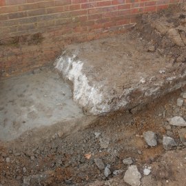 A photo taken from the Scenes of Crime Officer excavation. Notice the different layers. The top (white) layer is the concrete which Mark ordered, which has been described as of "amateur installation". Beneath this is the third (grey), professionally-laid layer of mortar. Two more layers lie under it. Forensic analysis shows that the workmanship involved, and materials used in these mortar layers are in stark contrast to Mark's work. Mark’s work was “less well-compacted and more voided at the upper and edge surfaces, suggesting a non-specialist installation and the absence of shuttering”. By comparison, the “mix quality and consistency (both thoroughness of mixing and degree of compaction) of the mortar layers suggests preparation by an experienced person”. According to the haulier’s own description, “I remember thinking he was out of his depth. He looked as though he had never used a wheelbarrow before. He clearly didn’t have a clue what he was doing”. Notice the smooth finish to the mortar. This would have appeared completely normal to Mark when he arrived on 17 November 2009. There was no reason for him to suspect that there was anything buried beneath.
