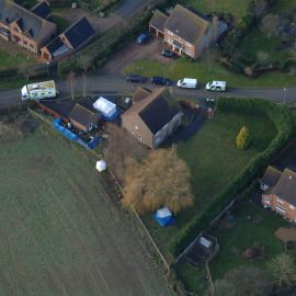 A close-up aerial shot of the garage area, facing the field. Notice the houses overlooking the front-doors of the garage.